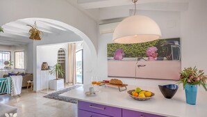 Een moderne keuken met een groot eiland, een zithoek met een bank en uitzicht op een roze flamingo standbeeld.
