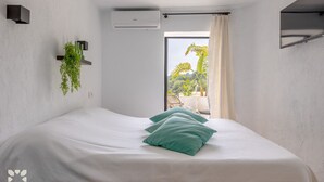 Een slaapkamer met een bed, een kamerplant en uitzicht op het landschap.