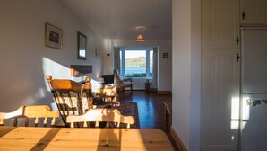 Un comedor con una mesa y sillas de madera, vistas por una ventana y una puerta blanca.