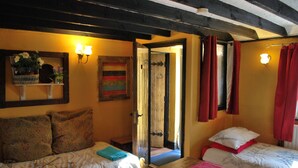 Una habitación con dos camas, un espejo y una puerta que da a otra habitación.