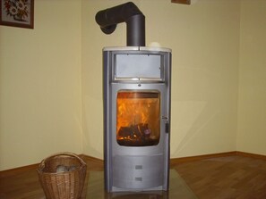 Ein Kaminofen mit Schornstein, ein Korb und ein gerahmtes Bild an der Wand.