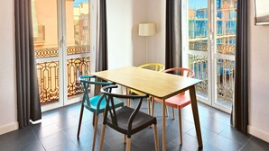 A dining area with a wooden table and four chairs, large windows with a view of buildings and construction, and a floor lamp. - Flats Friends Torres Quart 1 bedroom with terrace (Valencia)