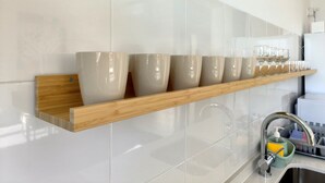 A kitchen with a wooden shelf holding several bowls and glasses, a stainless steel sink with a soap dispenser, and a tiled backsplash. - Flats Friends Torres Quart 1 bedroom with terrace (Valencia)