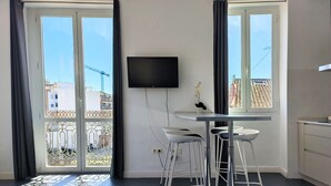 A modern room with a dining area, a TV mounted on the wall, and large windows offering a view of the cityscape. - Flats Friends Torres Quart 1 bedroom with terrace (Valencia)