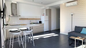 A modern kitchen with white appliances, a dining area with bar stools, and a living room with a sofa and a floor lamp. - Flats Friends Torres Quart 1 bedroom with terrace (Valencia)