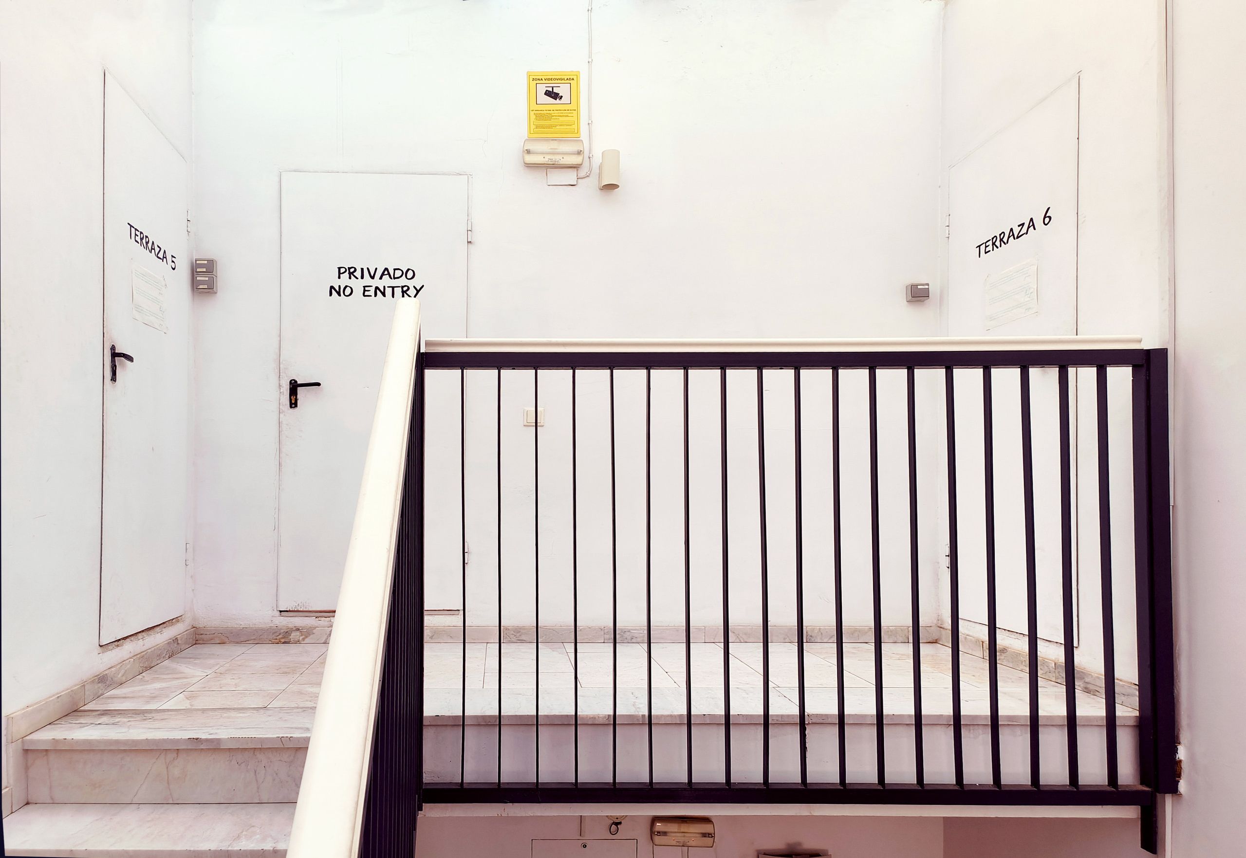 Una escalera con barandilla metálica que lleva a una puerta con la leyenda 'Privado No Entry'.