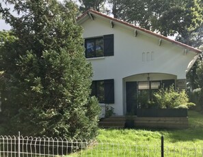 Ein zweistöckiges Haus mit weißer Fassade, dunklen Fensterläden und einem Ziegeldach.