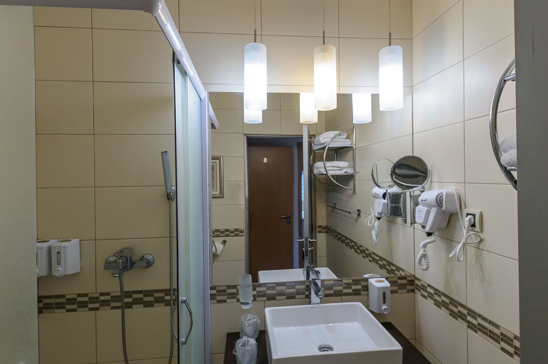 Un baño con lavamanos, espejo, toallero y secador de pelo.