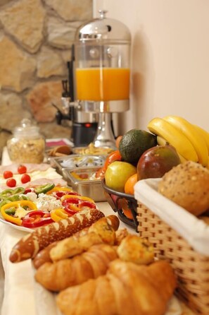 Un bufé de desayuno con diversas frutas, verduras, pasteles y una máquina de café.