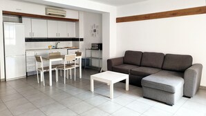 A compact living space with a kitchenette, a dining area, and a seating area with a sofa and ottoman.