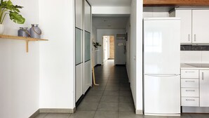 A modern kitchen with white cabinets, a white refrigerator, and a wooden countertop.