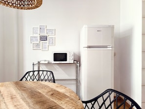 A compact kitchenette with a white refrigerator, a microwave, and a small sink. There are framed welcome and informational cards on the wall.