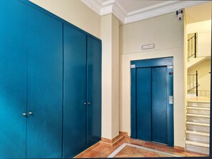 A hallway with two blue doors, a light fixture, and a staircase with a handrail.
