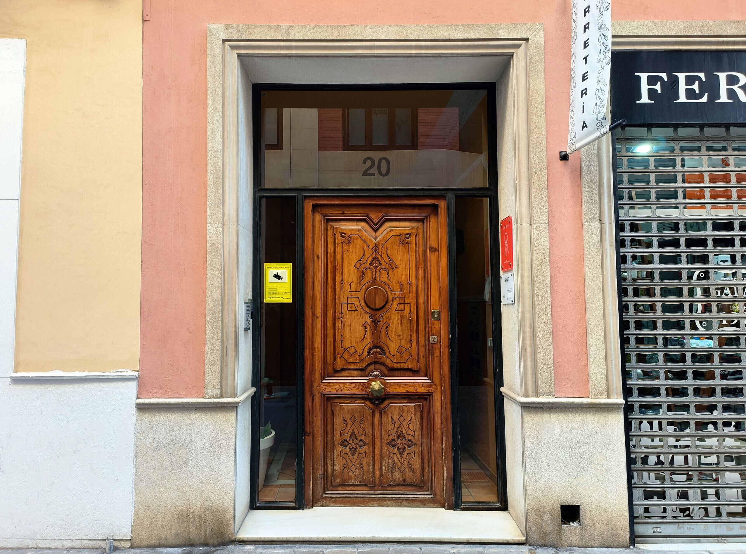 A wooden door with intricate carvings, a number '20' above it, and a sign indicating a parking area.