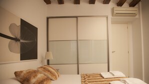 A bedroom with a bed, pillows, a lamp, and a large window.