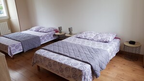 Ein Hotelzimmer mit zwei Einzelbetten, jeweils ausgestattet mit einem gemusterten Bettbezug und Kissen, einem kleinen runden Tisch mit einer Lampe und einem Holzboden.
