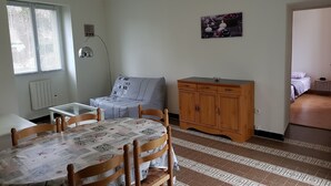 Ein Essbereich mit einem Tisch für vier Personen, einem Holzschrank und einem Bett im angrenzenden Zimmer.