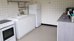 Eine Küche mit weißen Schränken, einem weißen Herd, einem weißen Kühlschrank und einer gefliesten Rückwand.