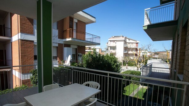 A balcony with a table and chairs, a view of neighboring buildings, and a clear sky. - M027 - Marcelli, three-room apartment with terrace 150 meters from the sea (Marcelli)