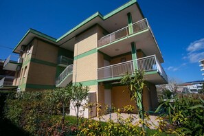 A multi-story building with balconies, a staircase, and a garden area.