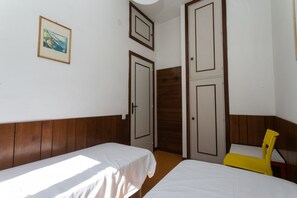 A room with two beds, wooden paneling, a framed picture, and a yellow chair. - M027 - Marcelli, three-room apartment with terrace 150 meters from the sea (Marcelli)
