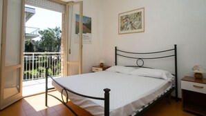 A bedroom with a bed, a nightstand, a lamp, and a balcony door. - M027 - Marcelli, three-room apartment with terrace 150 meters from the sea (Marcelli)
