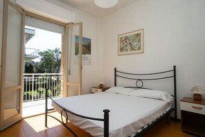 A bedroom with a bed, a nightstand, a lamp, and a balcony door.