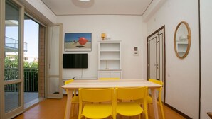 A dining area with a table and chairs, a television mounted on the wall, and a sliding glass door leading to an outdoor balcony. - M027 - Marcelli, three-room apartment with terrace 150 meters from the sea (Marcelli)