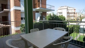 A balcony with a table and chairs, a green pillar, and a view of neighboring buildings. - M027 - Marcelli, three-room apartment with terrace 150 meters from the sea (Marcelli)