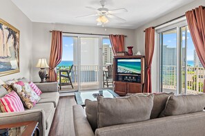 Un soggiorno con divano, tavolino, televisione e un balcone vista oceano.