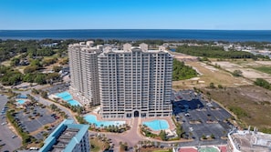 Un hotel di grandi dimensioni con numerosi piani, un cortile centrale con piscina e vista sull'oceano.