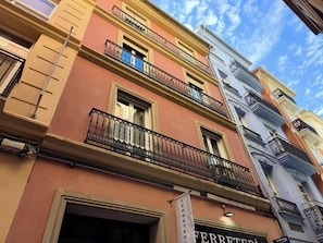 A multi-story building with balconies, a sign for 'FERRETERI', and a clear blue sky.