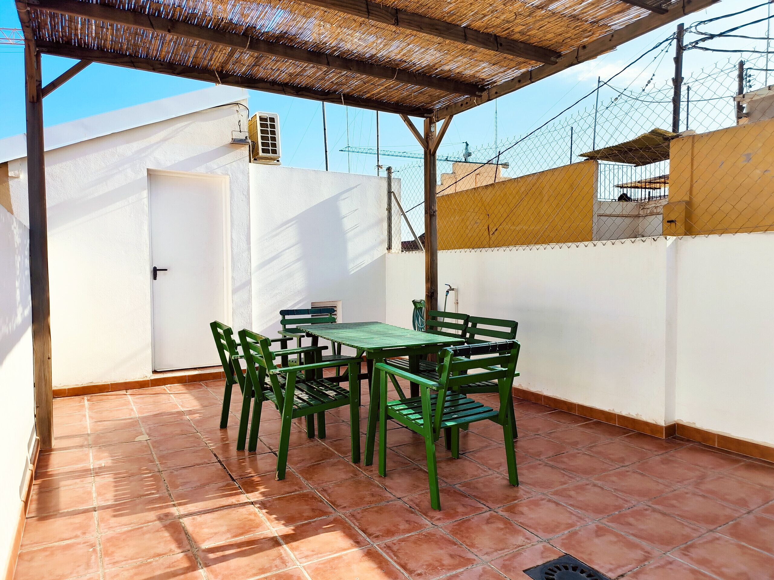 A patio with a table and chairs, a door, and a covered area with a roof.