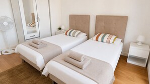 A double bed room with a wardrobe, bedside tables, and a standing fan. - L'appartement Rostro (Paris)