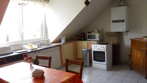 Una cocina con una mesa de comedor, sillas, estufa, microondas y fregadero.