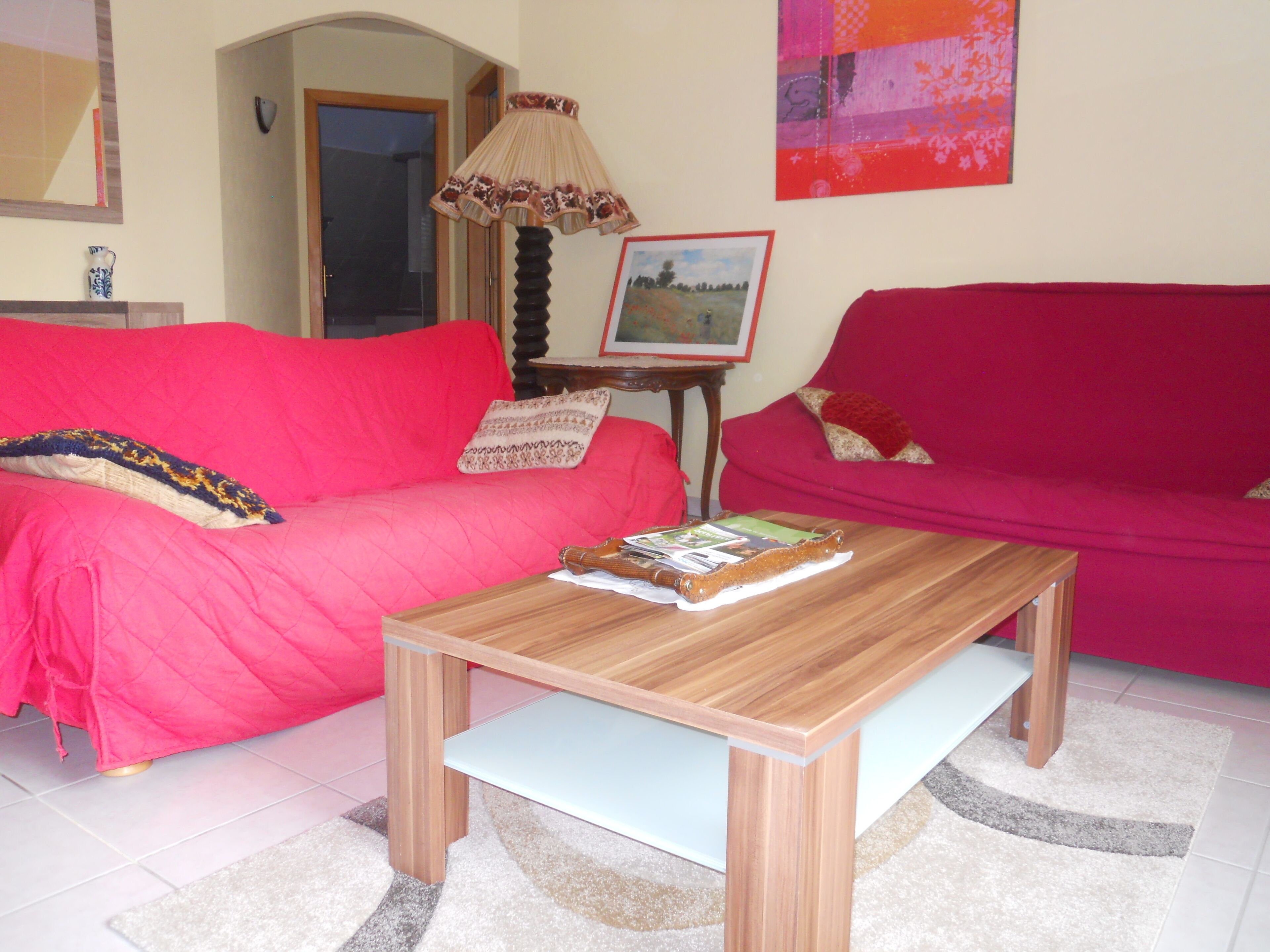 A living room with two red sofas, a wooden coffee table, and a framed picture on a small table.