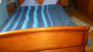Un dormitorio con una cama de madera, una mesita de noche, una lámpara y un aparador.