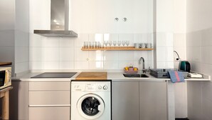 Eine moderne Küche mit Einbauwaschmaschine, Mikrowelle und einer Edelstahl-Dunstabzugshaube.