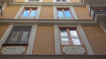 Un edificio de varios pisos con fachada amarilla, detalles blancos y molduras decorativas.