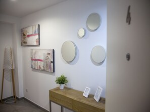 A reception area with a wooden console table, a potted plant, and three wall-mounted mirrors.
