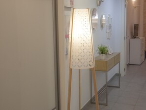 A hallway with a standing easel, a mirror, a potted plant, and a wooden cabinet.