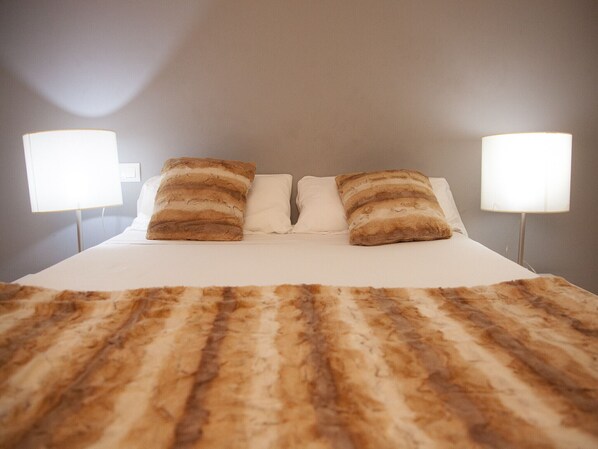 A bed with a striped blanket, two pillows, and two bedside lamps.