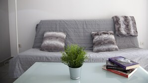 A modern living room with a grey sofa, a white lamp, and a glass coffee table with a potted plant and books. - Flats Friends Tetuan 2 bedrooms (Valencia)