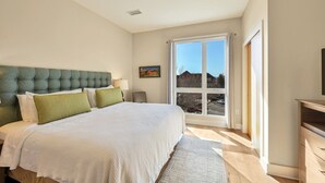 Een slaapkamer met een groot bed, een raam met uitzicht, een nachtkastje en een televisie.