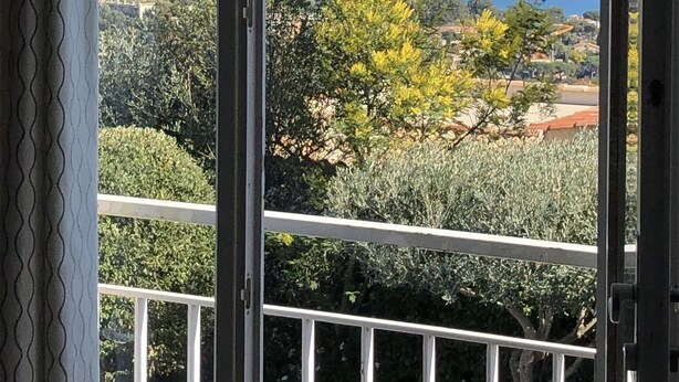 Une vue depuis un balcon doté d’une balustrade, donnant sur une étendue d’eau et des collines lointaines.