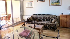 A living room with a sofa, a glass table, a chair, and a cabinet. There are two framed pictures on the wall. - Apartment for 6 persons with swimming-pool and tennis in condominium (Capbreton)