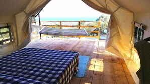 A tented accommodation with a bed, a hammock, and a view of the sea. - Agriturismo Erbe Matte - Campsite (Sant'Antioco)