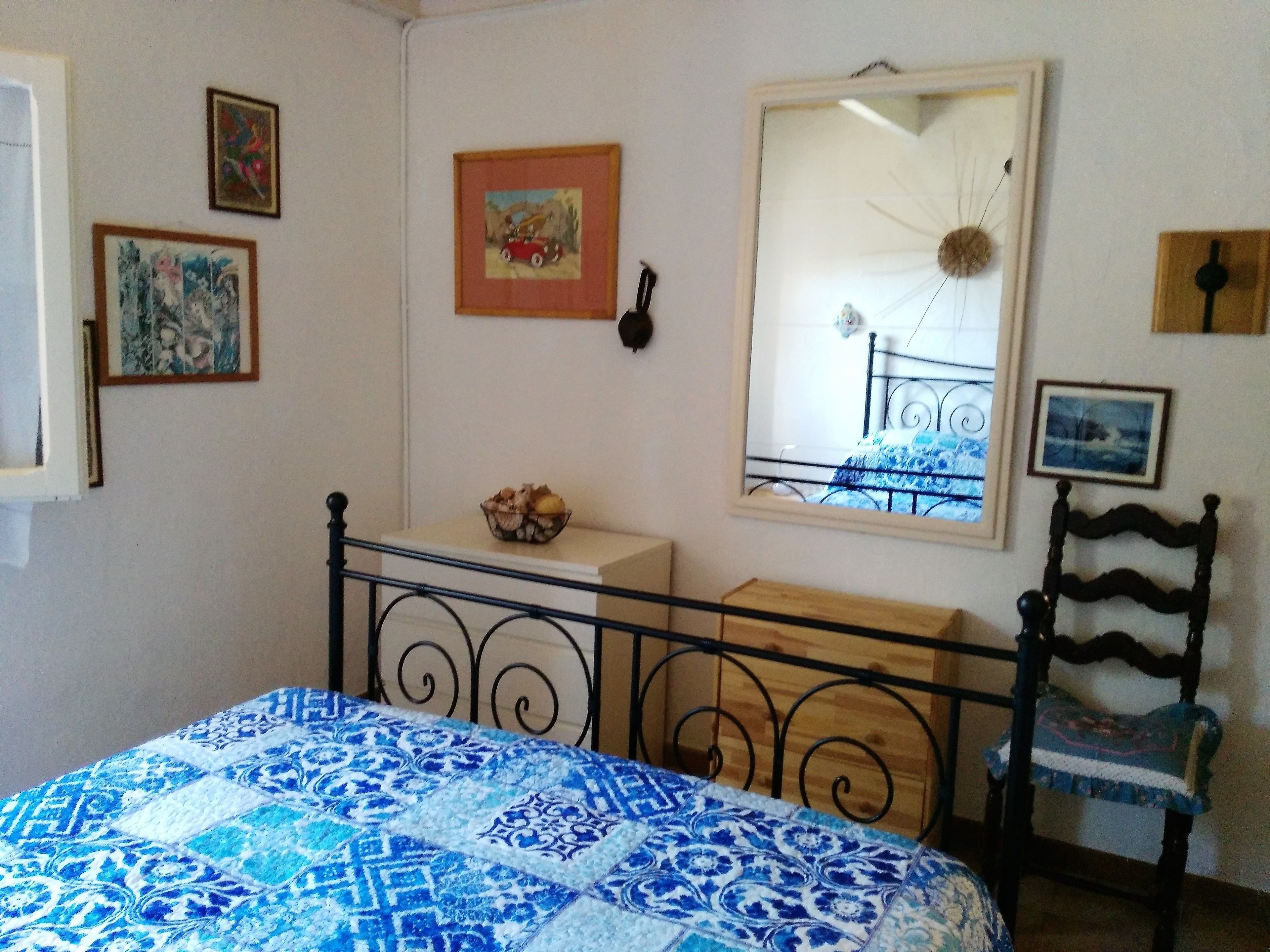Ein Schlafzimmer mit Bett, Sessel, Spiegel und einem kleinen Tisch.