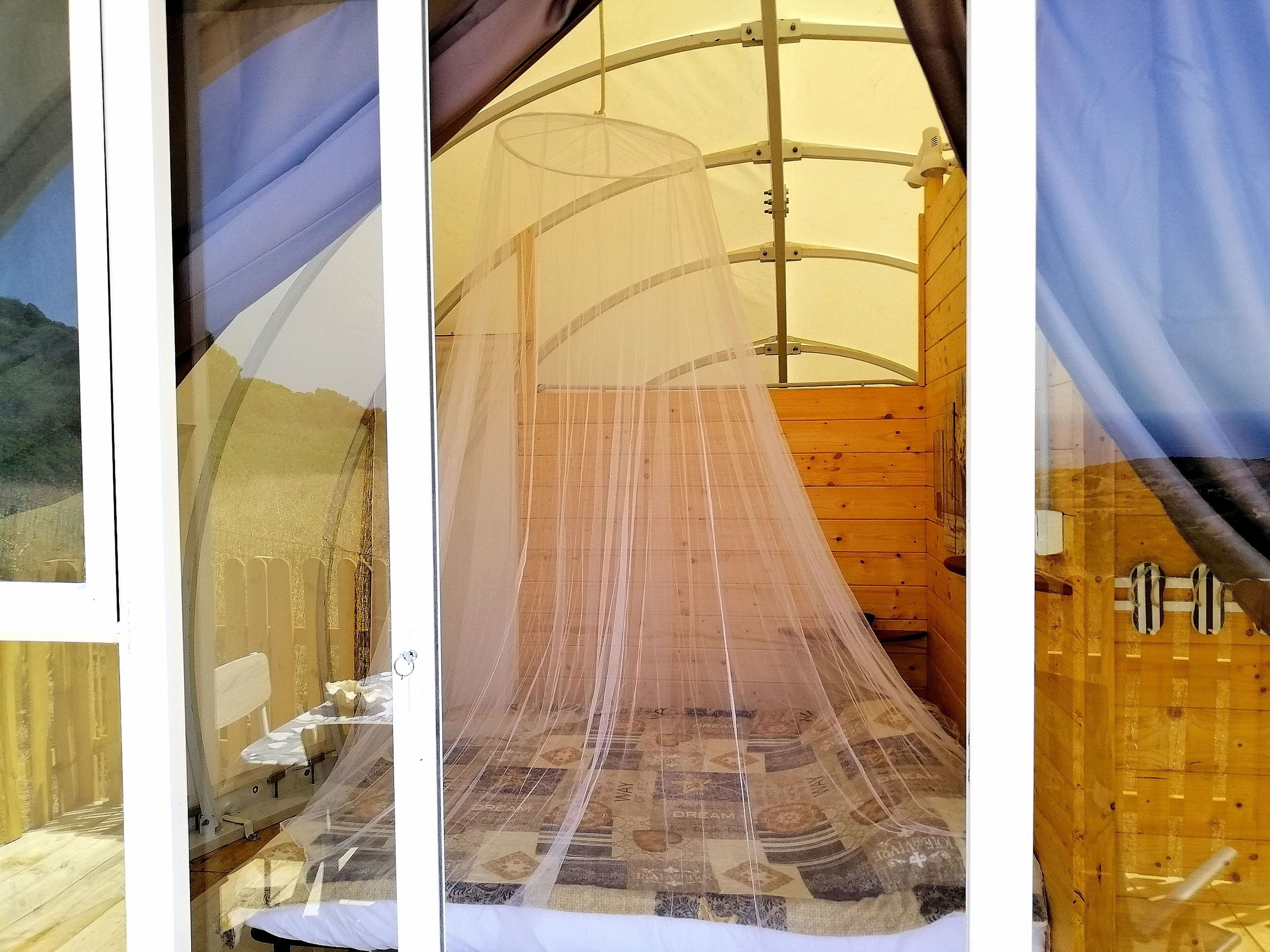 Una stanza con un letto, una parete in legno e una zanzariera.