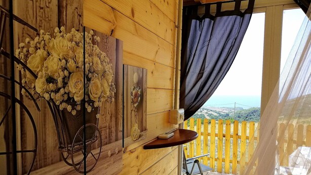 A wooden cabin interior with a balcony, a bicycle, and a vase of flowers. - Agriturismo Erbe Matte - Campsite (Sant'Antioco)